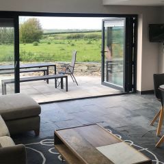 Brushed charcoal 600x400mm slate floor tiles_pictured in an open plan living room with open bifold doors looking out to countryside views