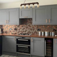Lunar copper and brass mosaic splashback wall tiles in a contemporary grey kitchen with copper accesories