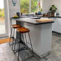 Natural charcoal grey slate floor tiles in a modern white kitchen with stools