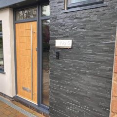Rustic black split face-large cladding the entrance door way of a property