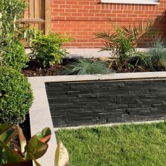 Rustic black split face mosaic tiles cladding outdoor garden planter with contrasting light grey coping stones