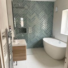 Vedra sea brick wall tiles fitted in a contemporay bathroom, creating a green coloured herringbone feature shower wall with complementing white floor tiles.