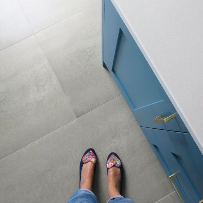 Person enjoying underfloor heating with urban grey concrete cement effect floor tiles in kitchen setting